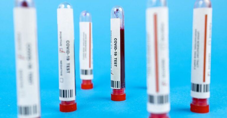 Close-up of COVID-19 blood test tubes on blue background, representing pandemic testing.
