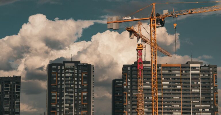 Construction site in Istanbul with cranes and buildings under a dramatic cloudy sky.