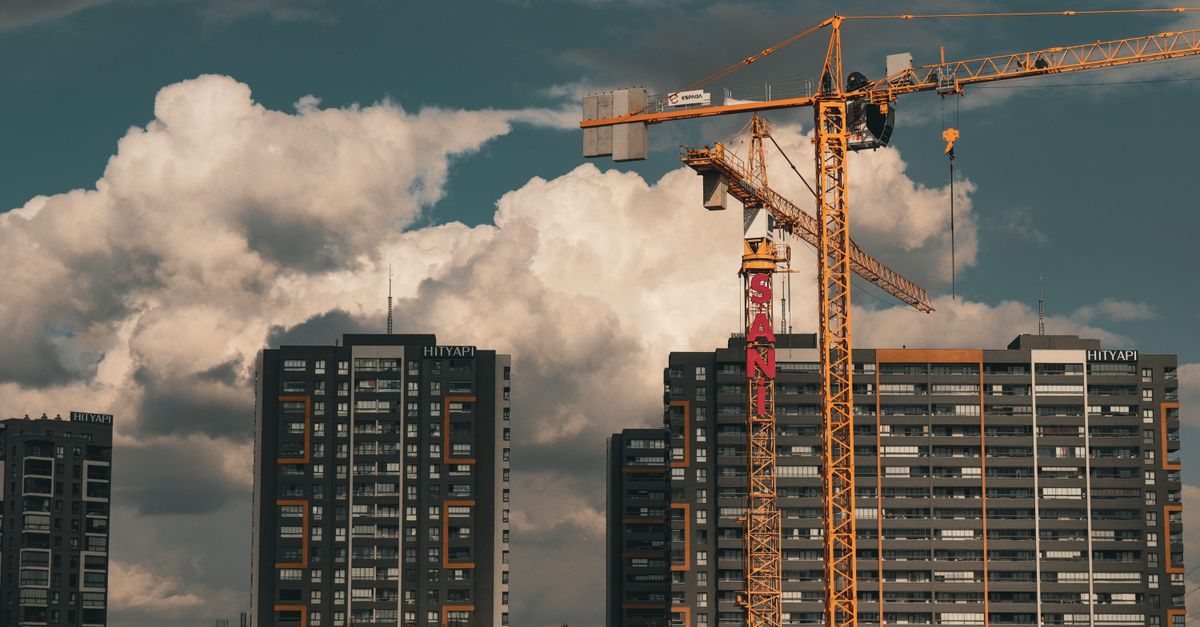 Construction site in Istanbul with cranes and buildings under a dramatic cloudy sky.
