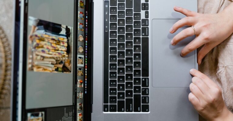 Close-up of hands using a laptop for photo editing, showcasing creativity in digital media.