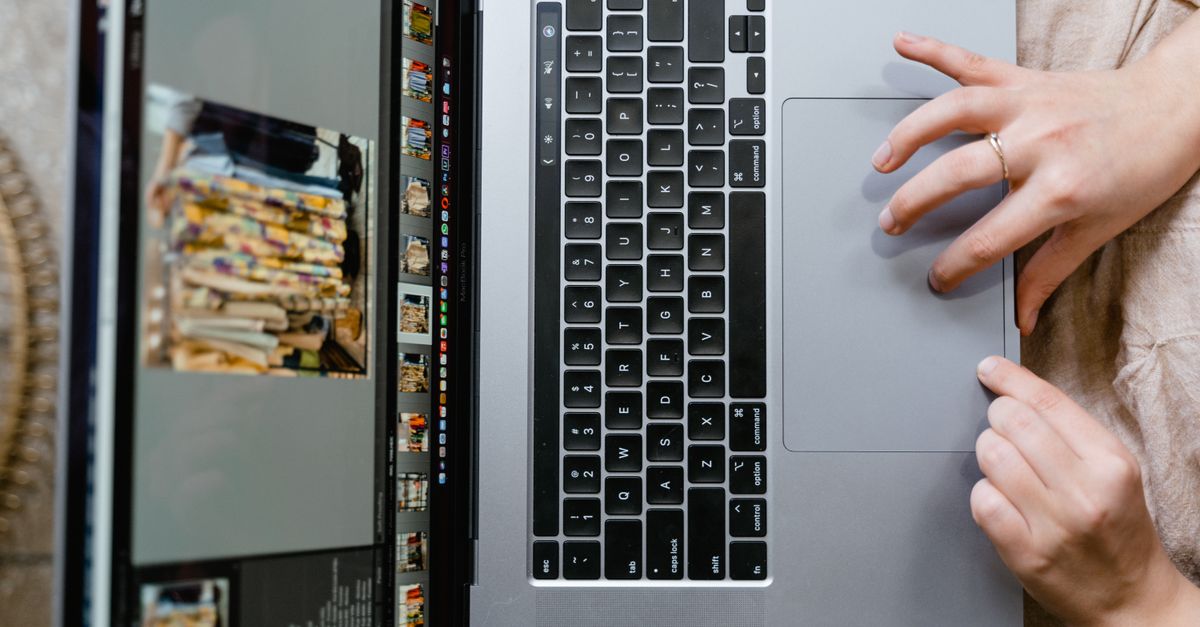 Close-up of hands using a laptop for photo editing, showcasing creativity in digital media.