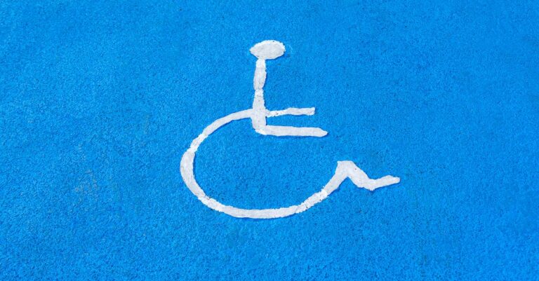 Clear blue disabled parking sign on asphalt surface, symbolizing accessibility.