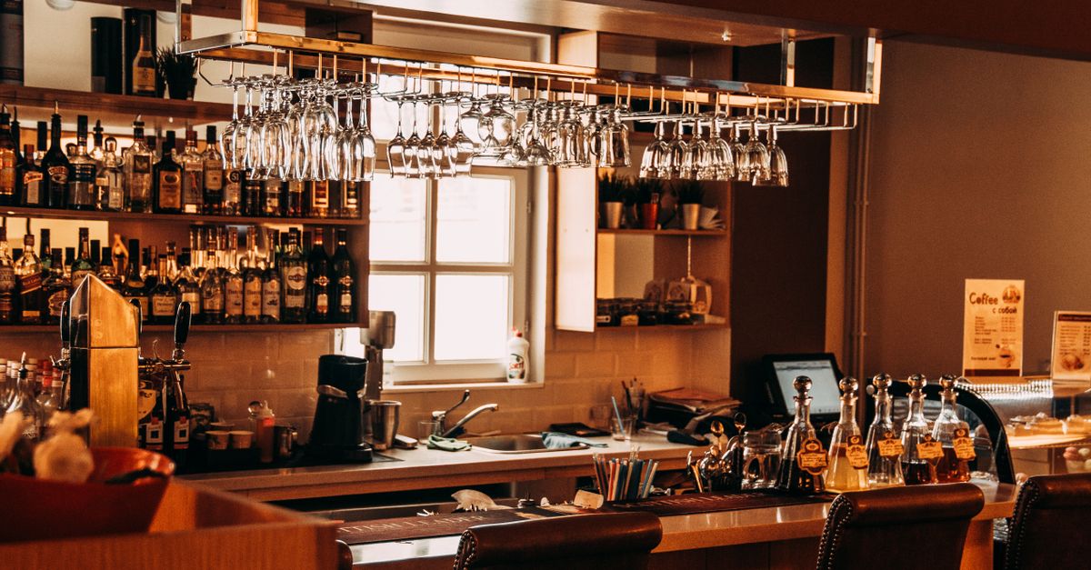 A stylish bar interior featuring hanging glassware, a range of spirits, and wooden furnishings.