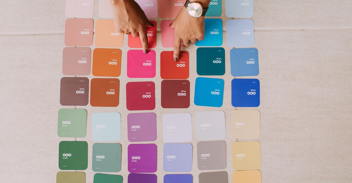 Top view of hands pointing at various color palette cards on a table, showcasing diverse options.