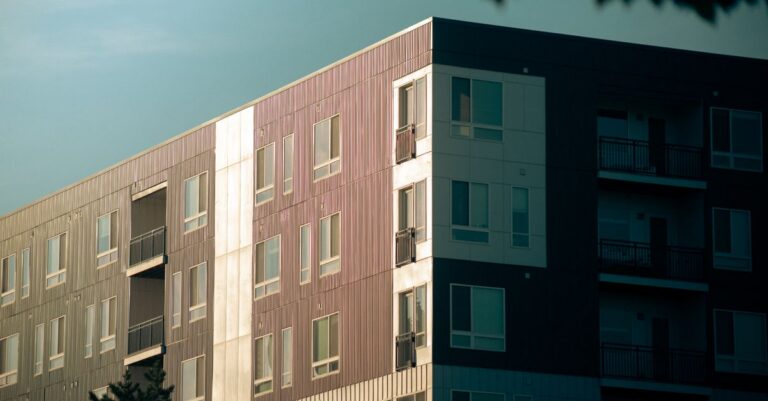 Contemporary urban apartment building with balconies and glass windows at sunset.