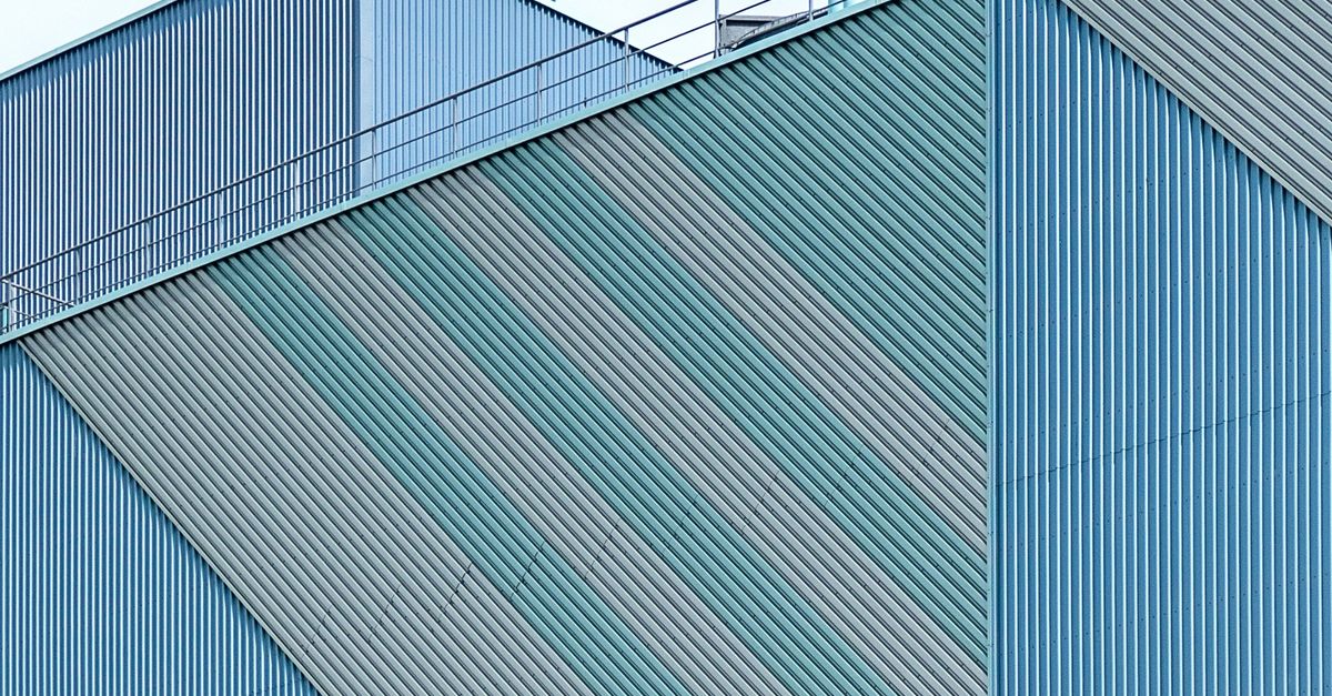 Close-up of a modern industrial building exterior with geometric metal panels and patterns.