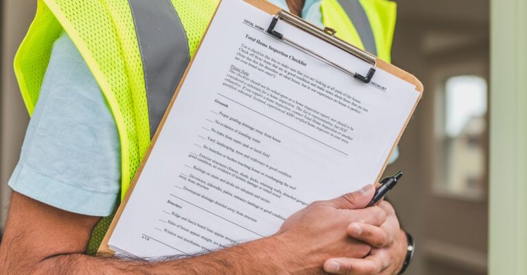Close-up of home inspector holding a checklist on a clipboard with a pen.