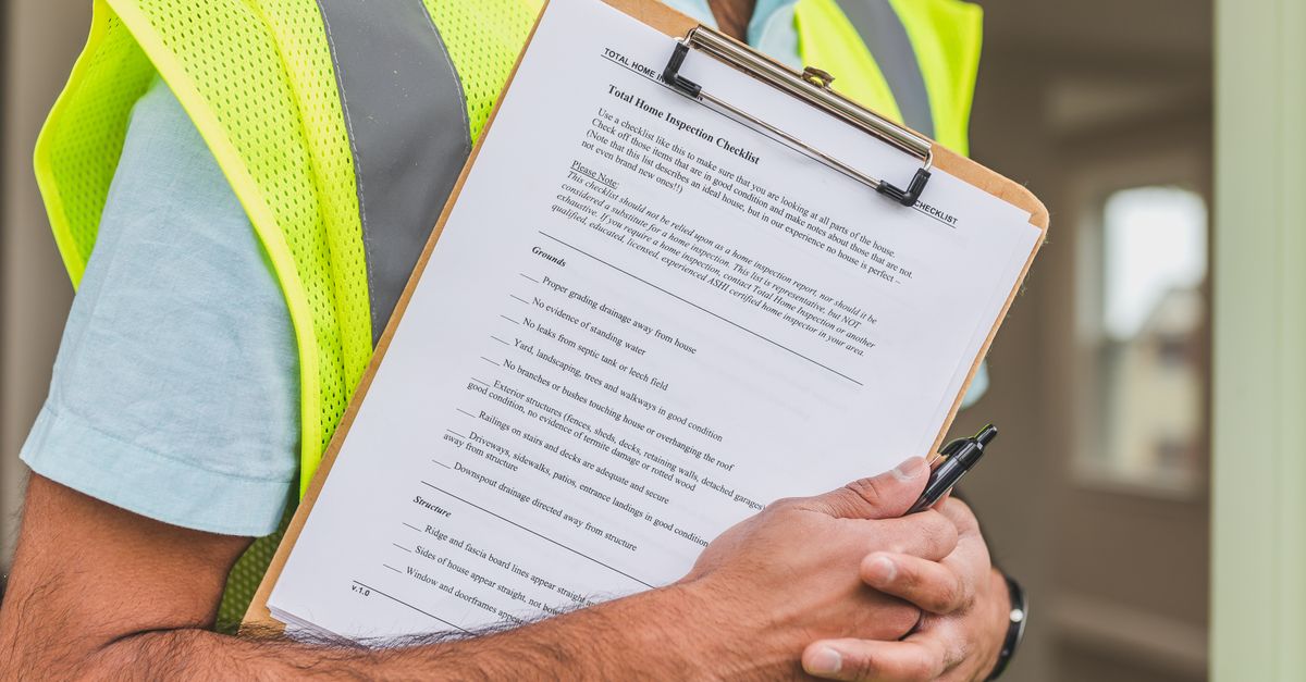 Close-up of home inspector holding a checklist on a clipboard with a pen.
