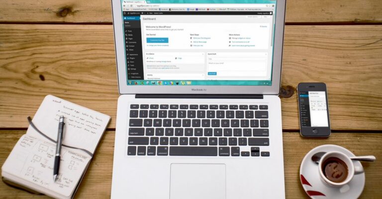 A cozy home office scene with a laptop, notebook, smartphone, and coffee, perfect for productivity.