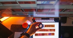 Top view of film negatives being reviewed with a magnifying glass on a light table in a photography darkroom.