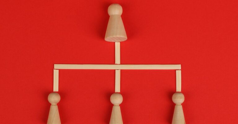 Conceptual depiction of hierarchy using wooden pieces on a vibrant red background.
