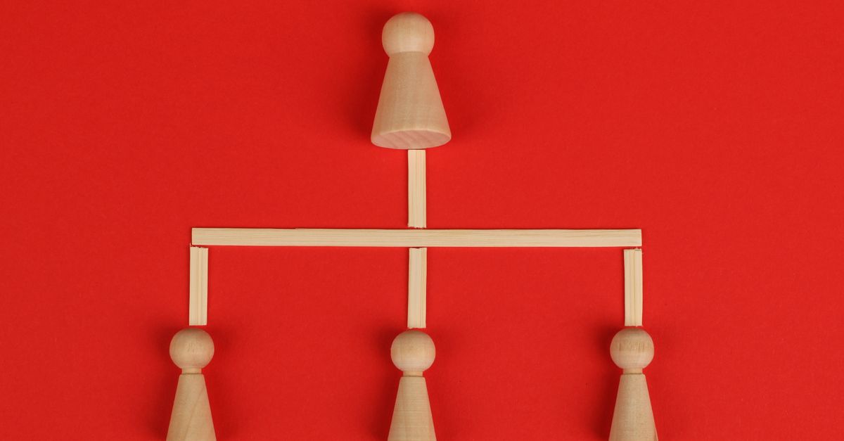 Conceptual depiction of hierarchy using wooden pieces on a vibrant red background.