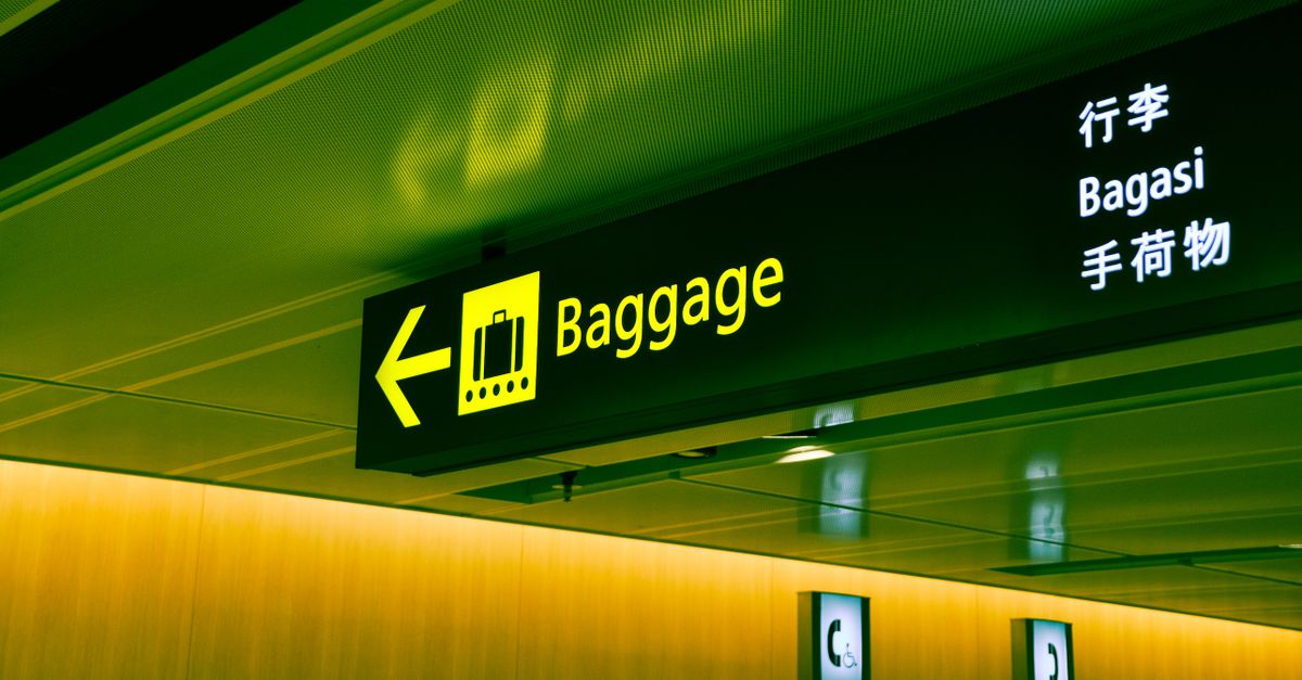 Illuminated airport baggage sign with multilingual translations pointing direction for travelers.